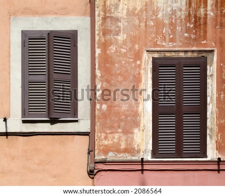Two asymmetric windows with brown shutters - beautiful architecture detail in Rome, Italy.