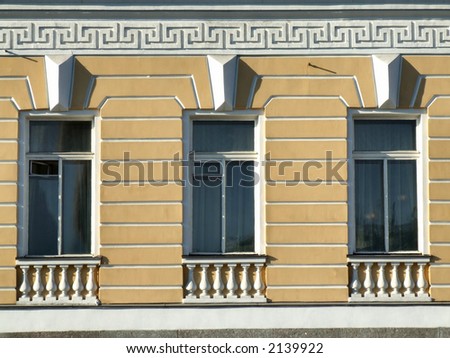 Three windows on a yellow wall - St. Petersburg historic building.