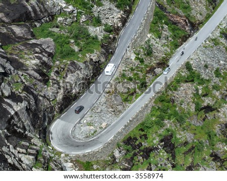 Narrow mountain road bend, some cars and a motorbike.