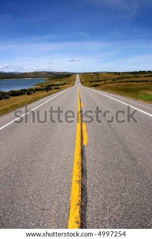 Straight prairie road in Alberta, Canada. Yellow line.