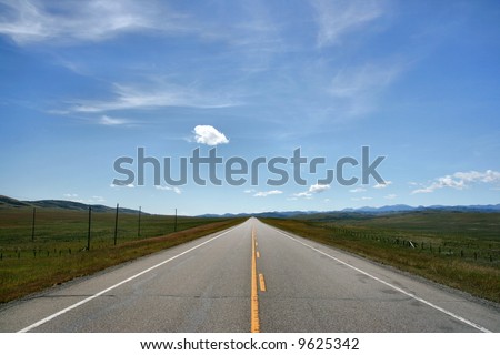 Straight prairie road in Alberta, Canada. Yellow line. Blue sky.