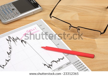 Stock market candle charts, remarks with a red marker, glasses and mobile smart phone