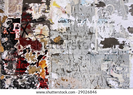 Torn posters on old wall, signs of graffiti, vandalism and urban decay