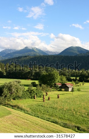 Countryside in Tirol, Austria. Haystacks, small wooden buildings and mountains in the background. Region of Stubaital and Stubaier Alpen.