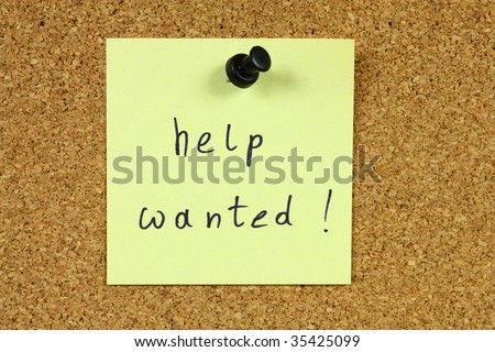 Yellow small sticky note on an office cork bulletin board. Employment and job opportunity concept. Looking for a new employee.