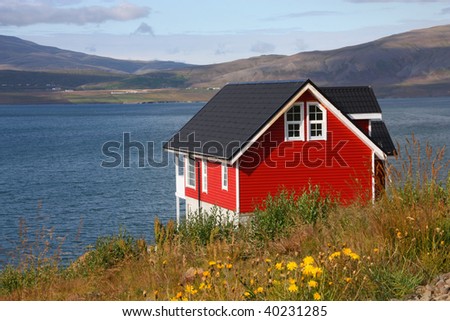 Small red generic home next to Hvalfjordur fiord in Iceland. Typical Nordic residential architecture.
