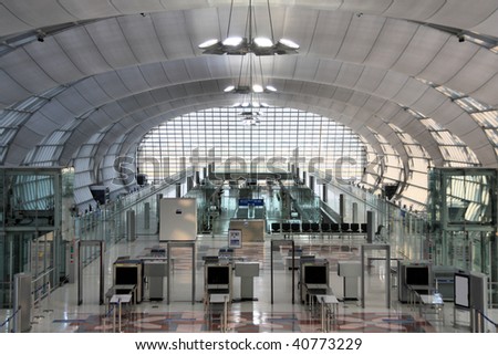 Modern interior of famous Bangkok Suvarnabhumi International Airport. Security control machines and departures area.