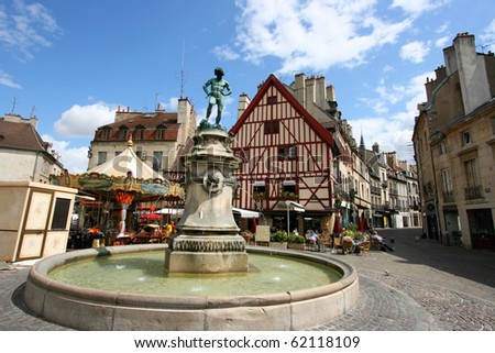 Famous fountain, characteristic houses and colorful carousel in Dijon, Burgundy, France. Place Francois Rude.