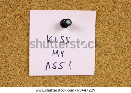 Office message, sticky note pinned to a bulletin board. Kiss my ass - rude, impolite message with offensive language.