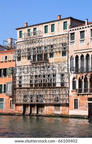 Venice, Italy. Safety scaffolding on old architecture, water canal and boats.