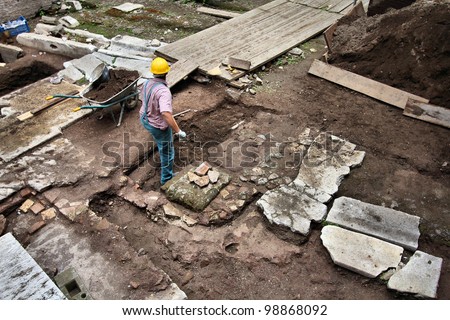 Rome, Italy - UNESCO World Heritage Site. Excavation worker digging around ancient Roman monument. Archeologist at work.