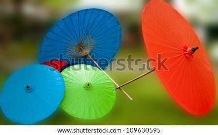 Four colored umbrellas. Two are bigger and two are smaller. One of them is red, one is green and two are blue.