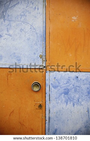 Orange and blue closed door, detail of a decorated door in the city, loneliness and abandonment