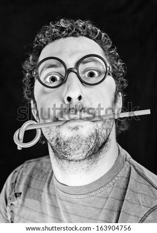 Adult man with glasses with a pen in his mouth, detail guy with a pencil with knot, surprise and creativity