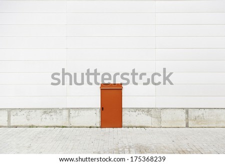 Red door in a wall, detail of a wall in an industrial building, closed, safety and security