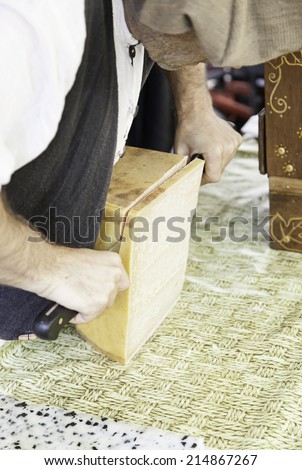 Cutting cheese on a market, detail of a person cutting pieces of cheese