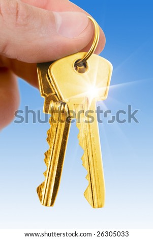 two gold keys in fingers over blue background
