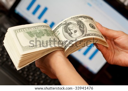 person shows money in hands near the laptop
