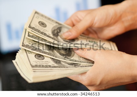 person counts money in hands near the screen