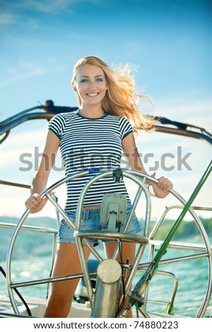 A beautiful young woman driving her powerboat around a Mediterranean coastline