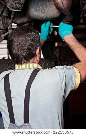 Mechanical repairs a car in the garage, unscrew a bolt.