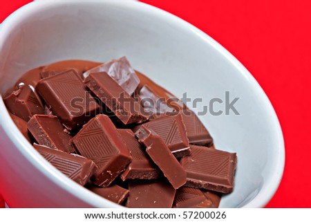 squares melted chocolate in a cup on a red background