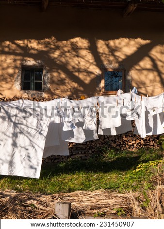 White laundry and baby clothes hanging to dry on a clothes line on the facade of the old traditional house