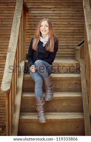 young woman is sitting on the wooden porch