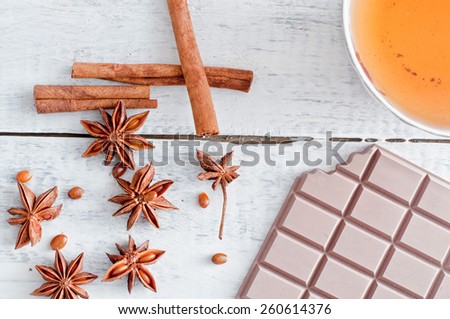 cinnamon stick, star anise, bar of chocolate and cup of tea on wooden table