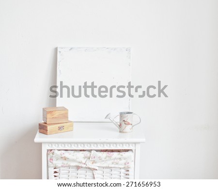 Home interior decoration with canvas, watering can and wooden boxes on the bedside table