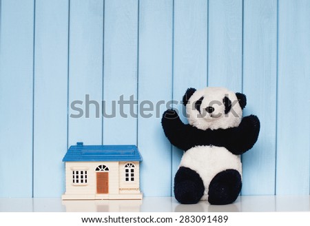 toy house and old vintage soft panda on the bookshelf in the children\'s room on blue wooden background