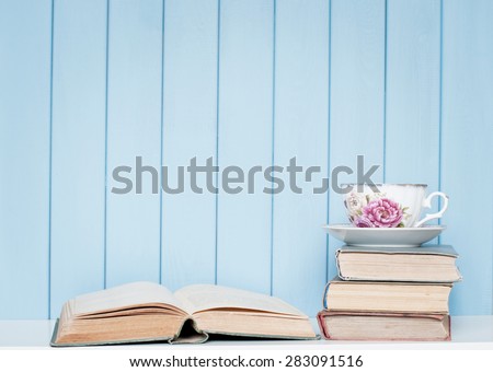 Old antiquarian ancient books and china cup on bookshelf on the blue wooden background