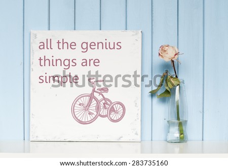 Motivating and inspiring  poster with quote All the genius things are simple and white rose in the bottle on blue wooden background