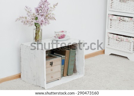 china teacup and gentle bouquet of lilac  on vintage shabby nightstand with wooden box and ancient books inside