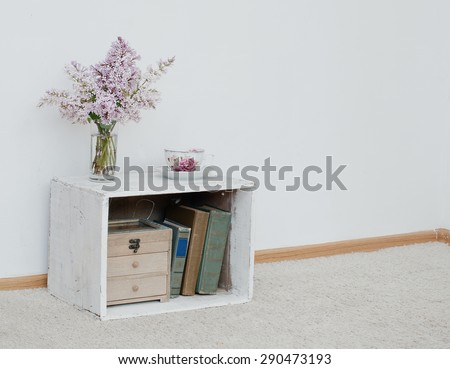 gentle bunch of lilac and china teacup on vintage shabby nightstand with wooden box and ancient books inside