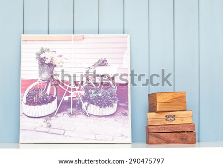 Vintage poster with bicycle - flowerbed and bunch of lilac on the table on blue wooden background