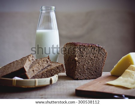 Food still life with sliced cheese, rye brown bread and bottle of fresh milk