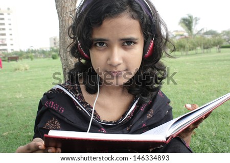 Young beautiful student reading book and listening music.