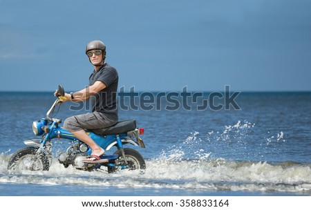 Weird biker.\
Strange biker on a moped driving along the seashore.
