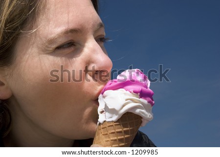 Young woman enjoying eating an ice cream on a blue background.