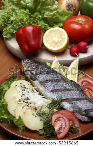 Trout in traditional restaurant setting, served with sliced potatoes,lemon and plenty of vegetables