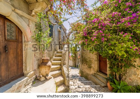 Fancy flower decorated narrow sunny street with stairs in old town in summer sunshine, Sicily, Italy