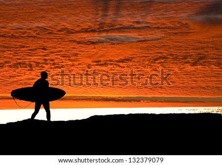 Surfer running on the cliffs at Santa Cruz, heading for the Pacific ocean as the sun sets to get in one final ride