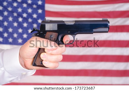 close up of a mans hand holding a 45 ACP 1911 over an American flag