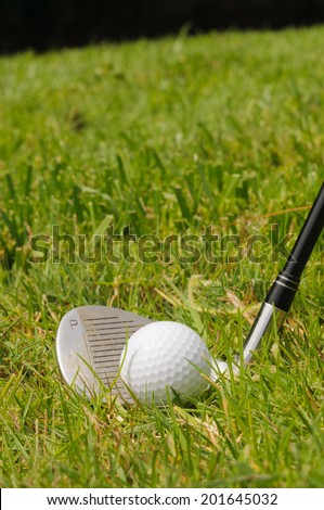 Golf ball on a tee with pitching wedge