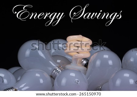 A pig-tailed fluorescent energy saving, green energy, low carbon footprint light bulb nestled in a group of old incandescent bulbs over a black background with room for your text