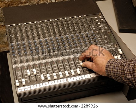 Operator adjusting sound levels on an audio board