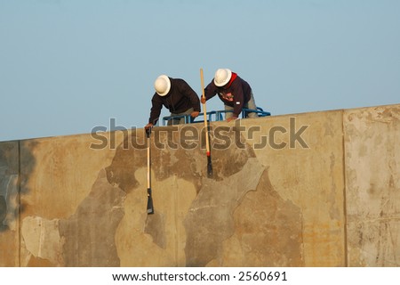 Construction workers cleaning cement wall