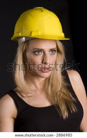 sexy blond female construction worker with hard hat and tool pouch on black background