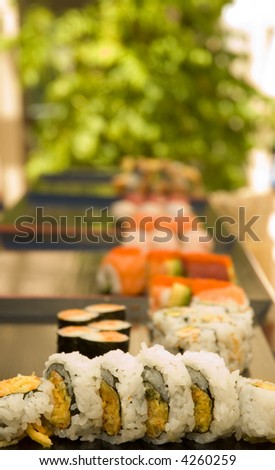 A series of sushi plates at an outdoor venue with a shallow depth of field